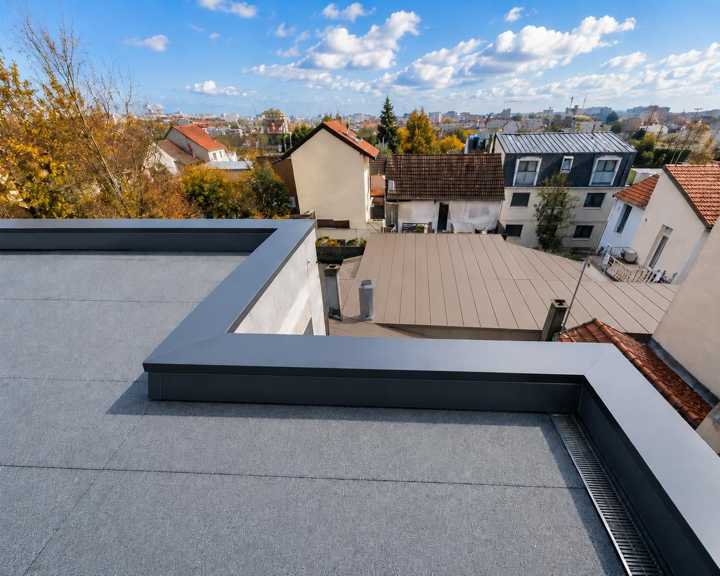 Couvertine anthracite ceinturant une toiture-terrasse, formant un angle net au-dessus de l'étanchéité.